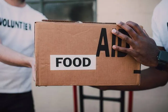 A volunteer's hands holding a cardboard box labeled Food Aid
