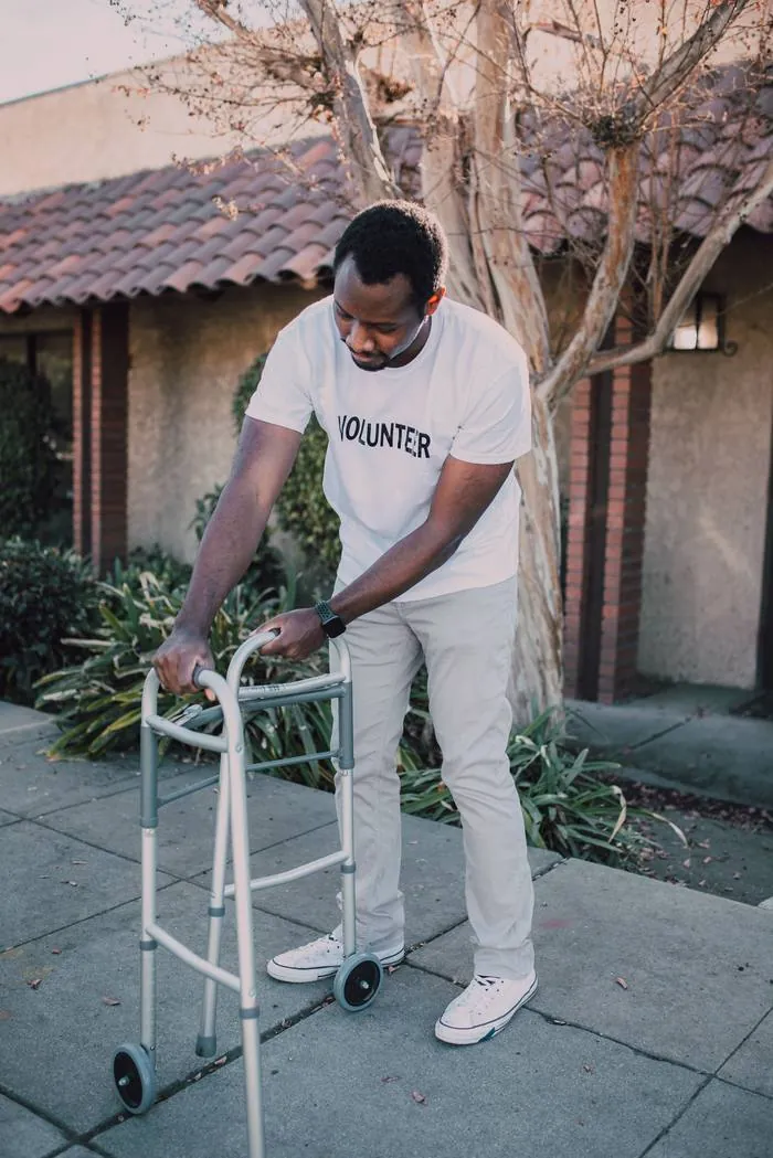 A volunteer wearing a Volunteer t-shirt helping someone with a walker