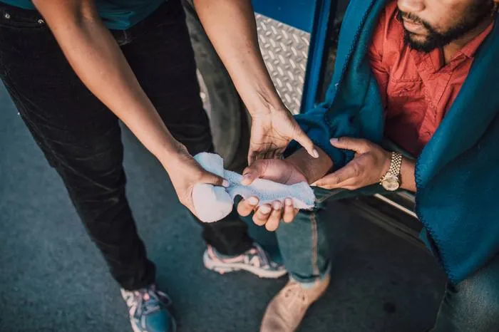 One person carefully bandaging another person's hand